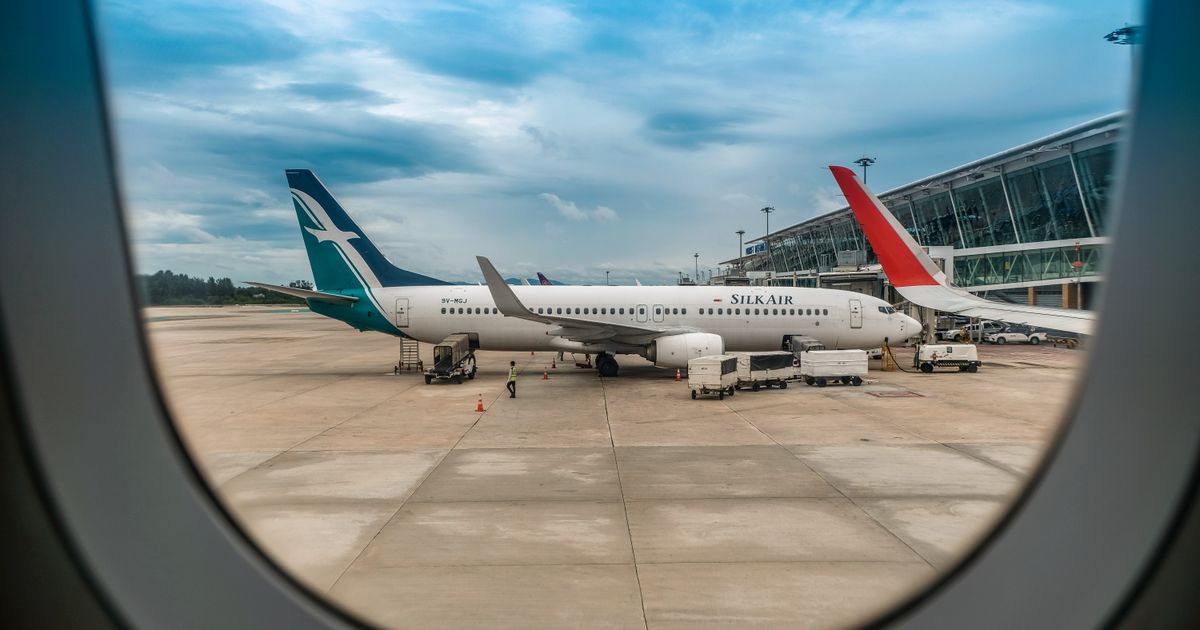 View of airplanes on a tarmac from an airplane window under a blue sky.