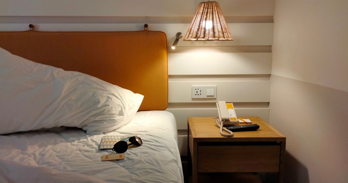 Inviting bedroom space with a lamp-lit nightstand, phone, and sunglasses on the bed.