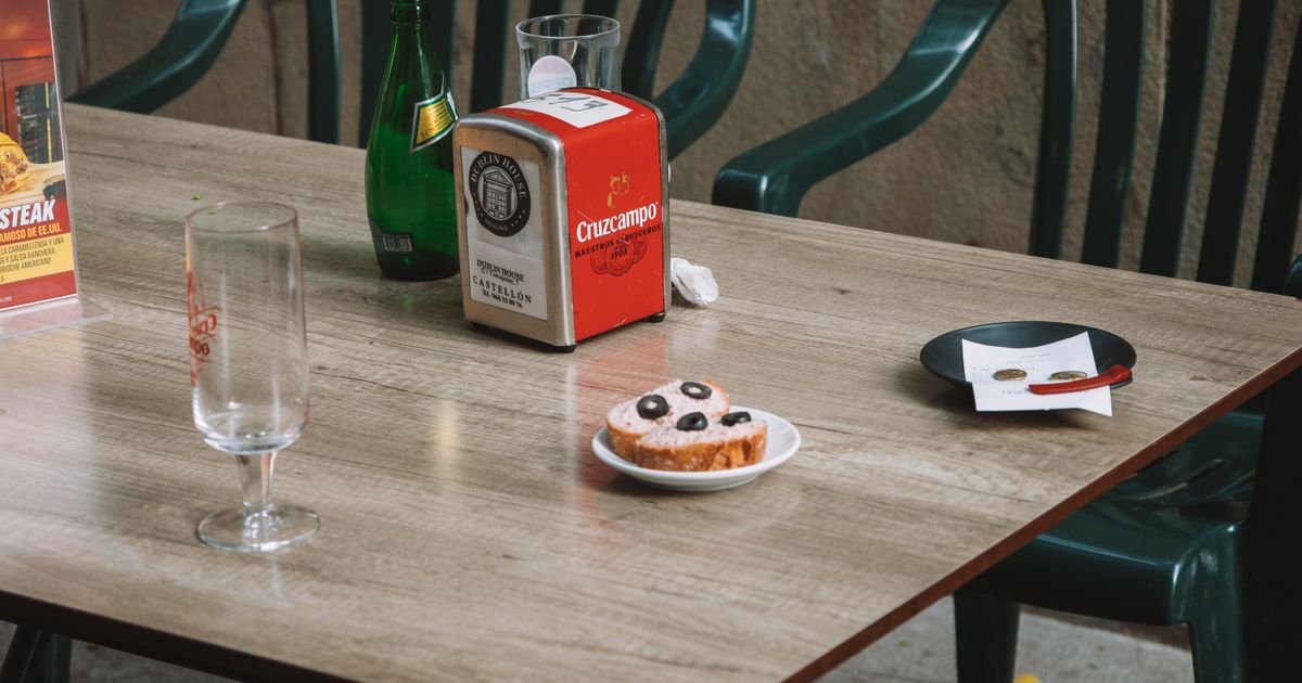 Casual outdoor cafe table setting in Valencia, Spain with drink and pastry.