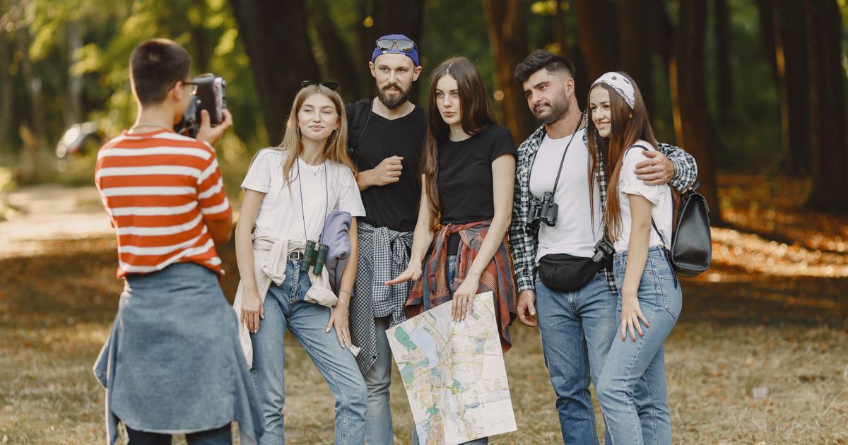 Young friends enjoying outdoor adventure in a forest, posing with a map for a memorable photo.
