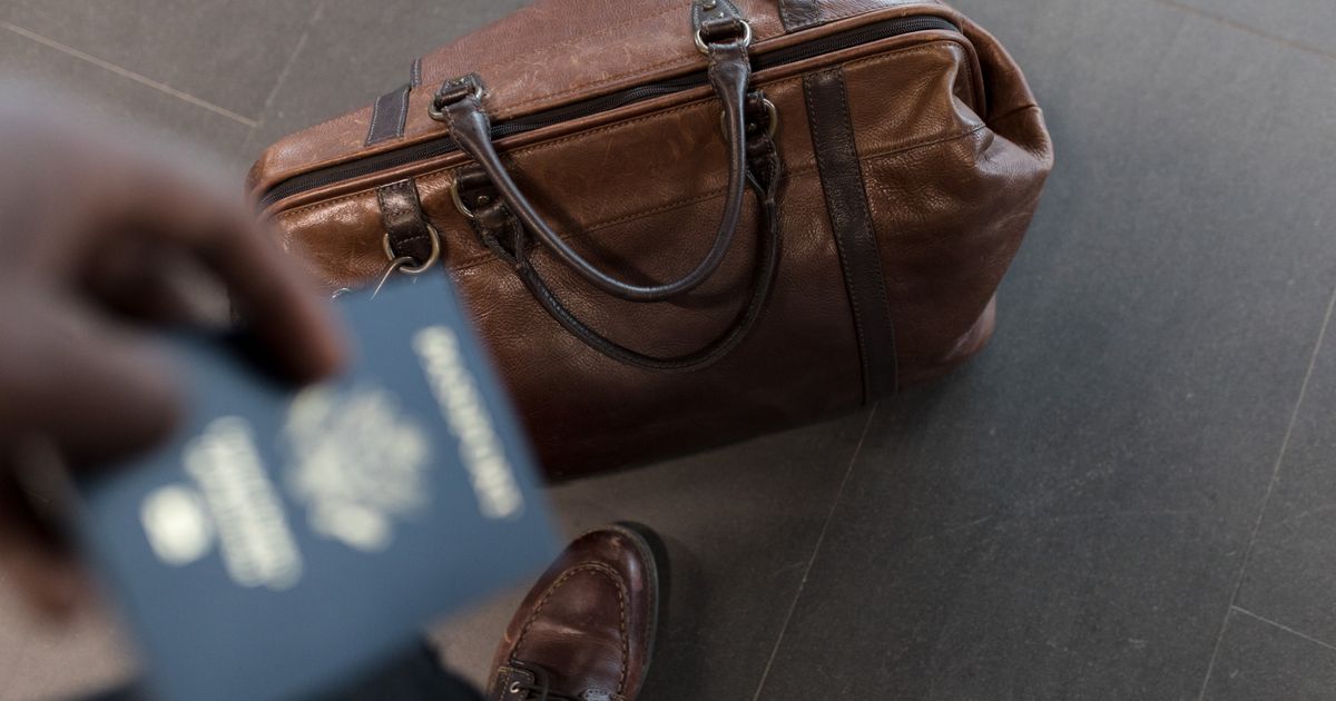 Brown leather bag with passport in an airport setting, ideal for travel and fashion themes.
