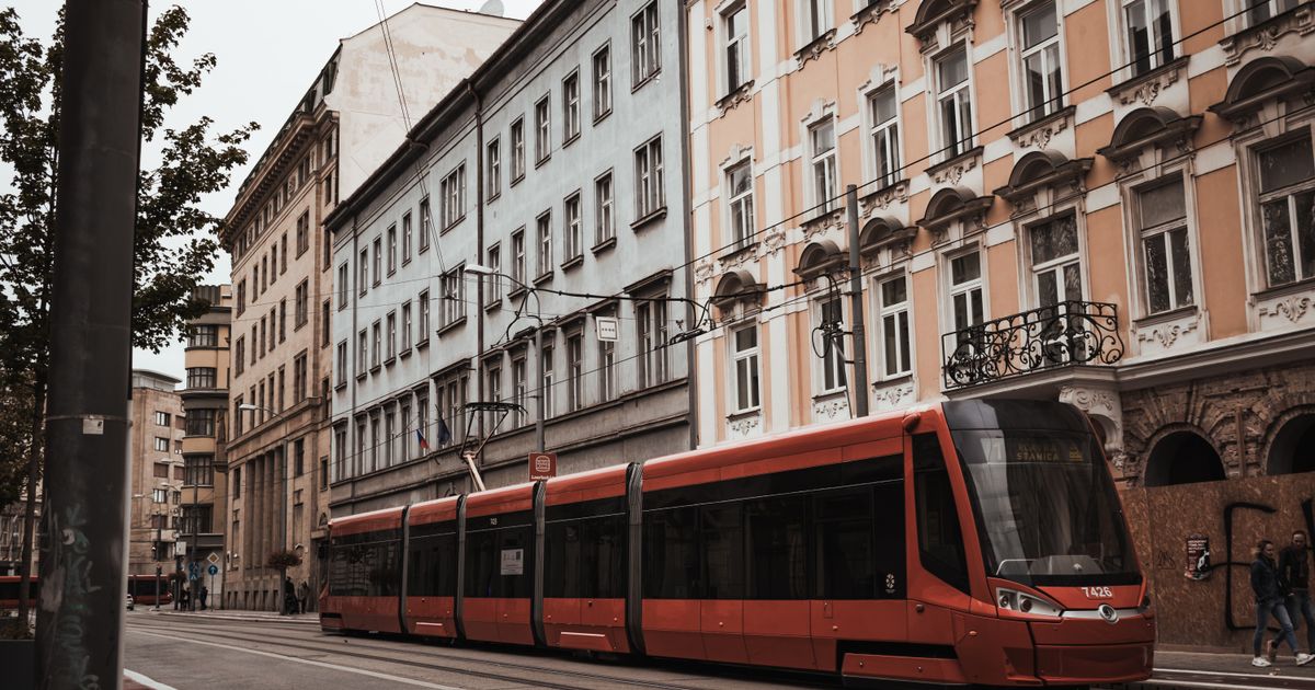 Explore the charm of Bratislava's streets with this classic view of a red tram passing by historic facades.